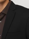 Close-up van de revers en borstzak van een zwarte JACK & JONES blazer, gedragen over een bruine blouse.