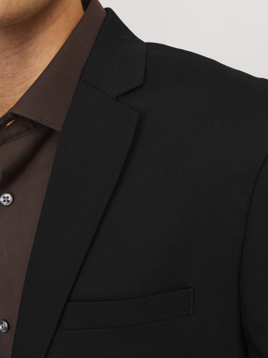 Close-up van de revers en borstzak van een zwarte JACK & JONES blazer, gedragen over een bruine blouse.
