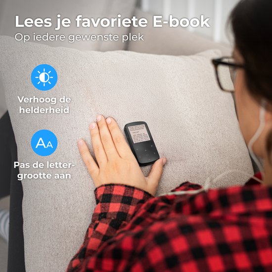 Persoon op een bank met een bril, lezend op een zwarte MP3-speler met instelbare helderheid en lettergrootte.