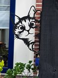 Zwart metalen kattenfiguur dat om een houten paal gluurt, met grote, ronde ogen en een speelse uitdrukking.