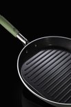Detail van een zwarte grillpan met prominente ribbels en lichtgroen handvat.