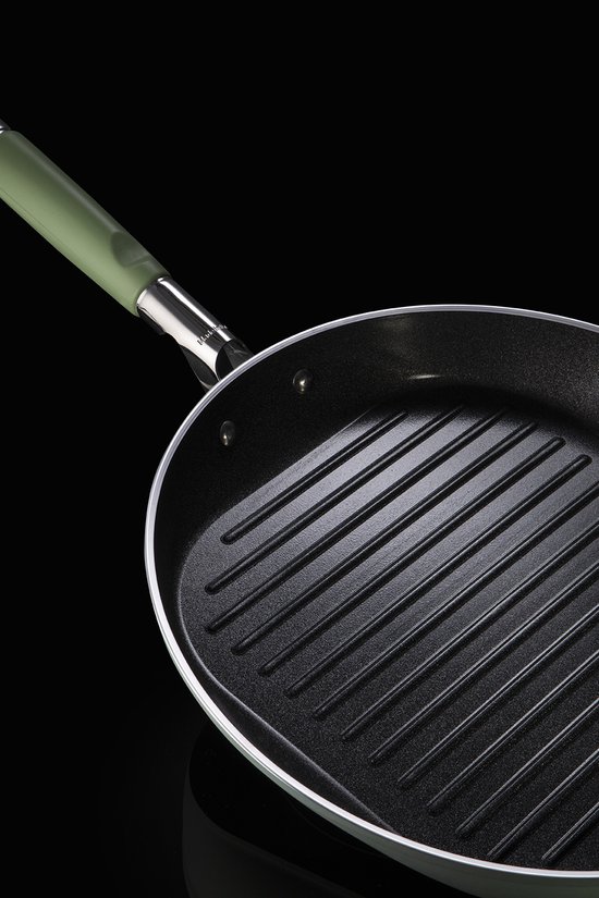 Detail van een zwarte grillpan met prominente ribbels en lichtgroen handvat.