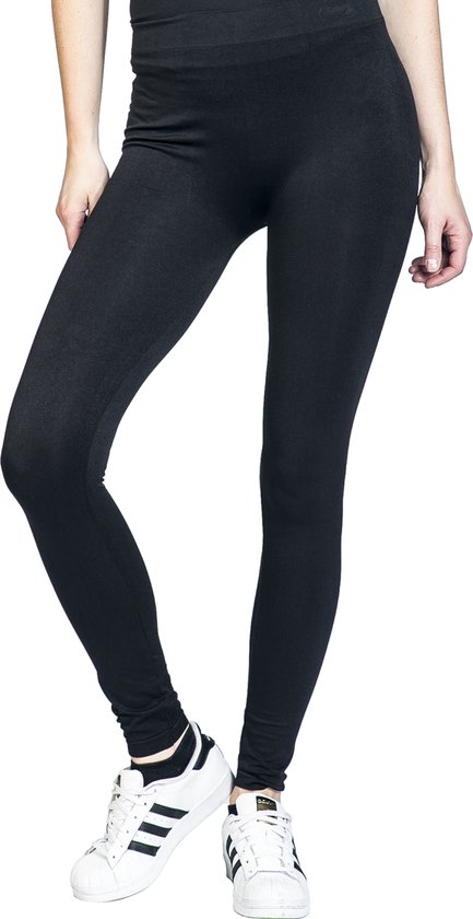 Model in een zwarte legging en witte sneakers.