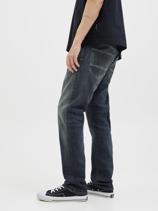 Zijaanzicht van een man in donkere jeans en sneakers.