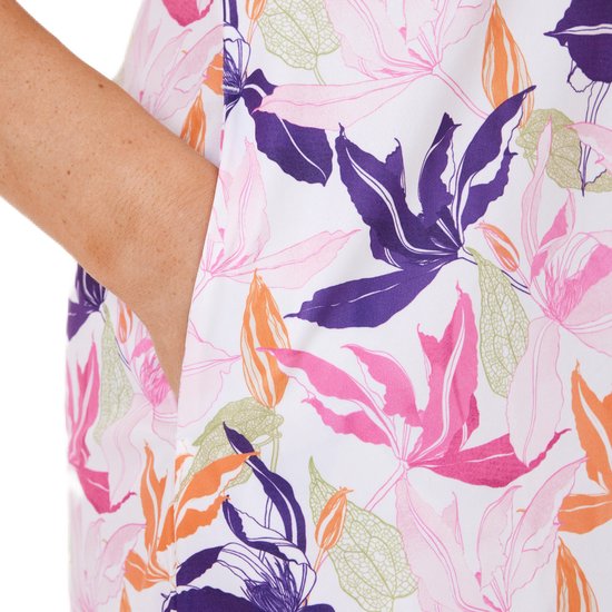 Close-up van de zijnaad van een witte jurk met een bloemenprint in roze, paars, oranje en groen, met een hand in de steekzak.