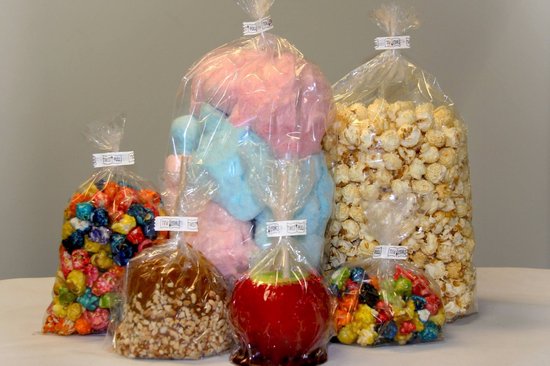 Vijf verpakkingen met zoetwaren: popcorn, suikerspin, karamelappels en kleurrijke snoepjes.