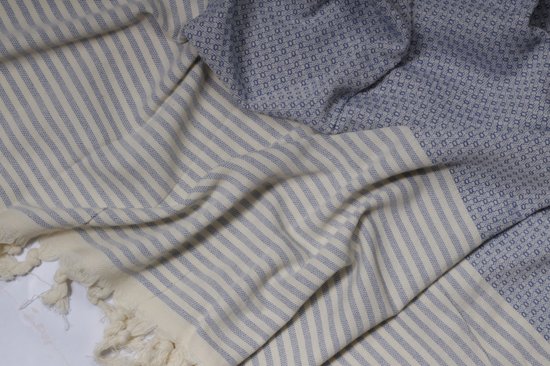 Gedrapeerde blauwe en witte gestreepte hamamdoek met een gedeelte met een blauw ruitpatroon.