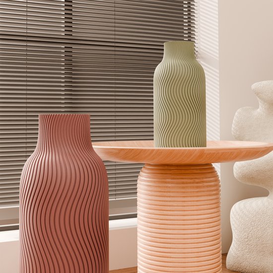 Vase brun-rouge et vert olive à motif ondulé sur une table d'appoint en bois.