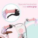 Roze kinderfiets met mandje, strikjes en speciale handvatten.
