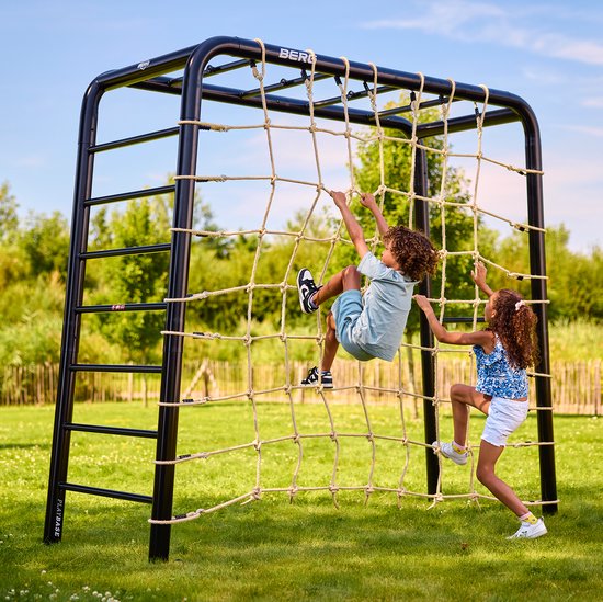 Twee kinderen klimmen op een zwart klimrek met een beige klimnet in een groene tuin.