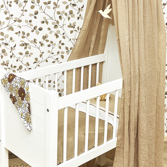Witte spijlen wieg met taupe sluier en bloemenprint dekentje.
