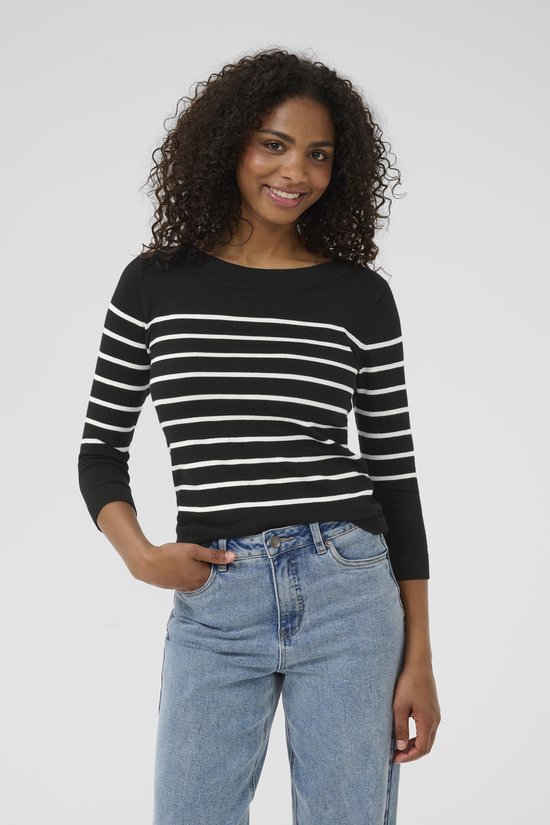 Model met een zwarte trui met horizontale witte strepen en driekwart mouwen, gecombineerd met jeans.