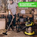Een man met een baard die een werkplaats opruimt met een gele en zilveren stofzuiger.