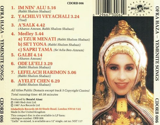 Ofra Haza in een traditionele, gouden en beige hoofdtooi versierd met munten, kralen en stof. Achtergrond met tekst.