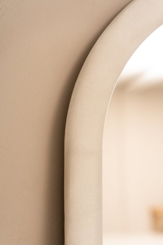 Close-up van een gebogen, beige, fluwelen spiegelrand.