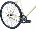 Achterwiel, ketting en pedalen van de crèmekleurige damesfiets. Ketting en tandwielen zwart.