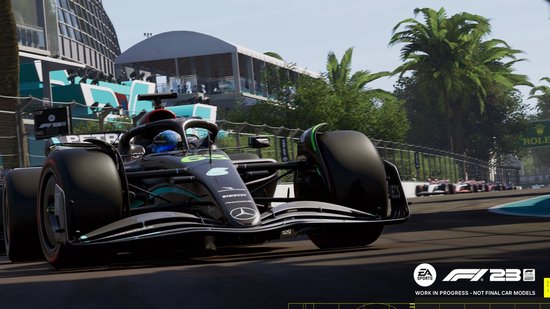 Zwarte F1 auto met nummer 65 en groene accenten op een zonnig racecircuit.