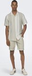Man draagt een beige kortarmig gestreept overhemd en beige shorts.
