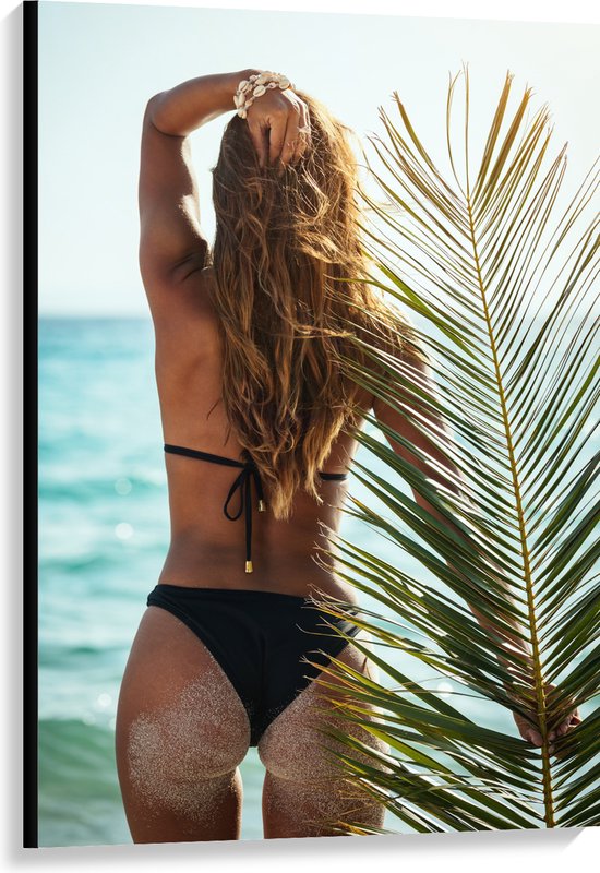 Canvas - Achteraanzicht van Vrouw in Bikini aan Zee met Palmblad - 80x120 cm Foto op Canvas Schilderij (Wanddecoratie op Canvas)