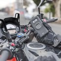 Hand met Quad Lock telefoonhoesje boven een Quad Lock motor stuurbevestiging.