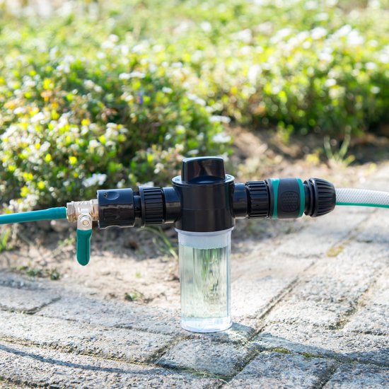Waterfilter met groene slang en zwarte aansluitingen, op een stenen ondergrond.
