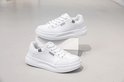 Twee witte lage sneakers met veters en dikke zool, de ene bovenop de andere.