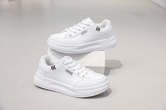 Twee witte lage sneakers met veters en dikke zool, de ene bovenop de andere.