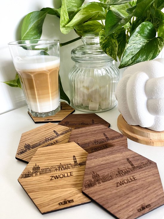 Houten zeshoekige onderzetters met skyline van Zwolle, rondom een glas koffie, een pot suiker en een plant.