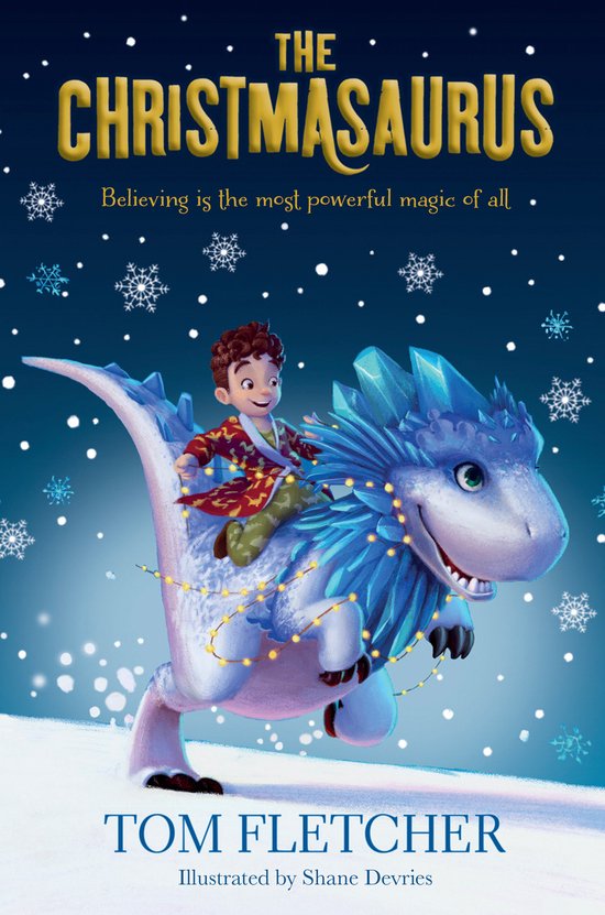 De voorkant van het boek 'The Christmasaurus'. Een jongen in een kerstpyjama rijdt op een blauwe dinosaurus versierd met kerstlichtjes en ijskristallen. Sneeuwvlokken vallen op de achtergrond. Tekst: 'THE CHRISTMASAURUS', 'Believing is the most powerful magic of all', 'TOM FLETCHER'.