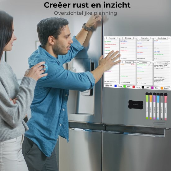 Koppel bij een koelkast die een magnetische weekplanner toont. Planbord met dagen, boodschappenlijst en notities, met een vrouw en man die erop wijzen.