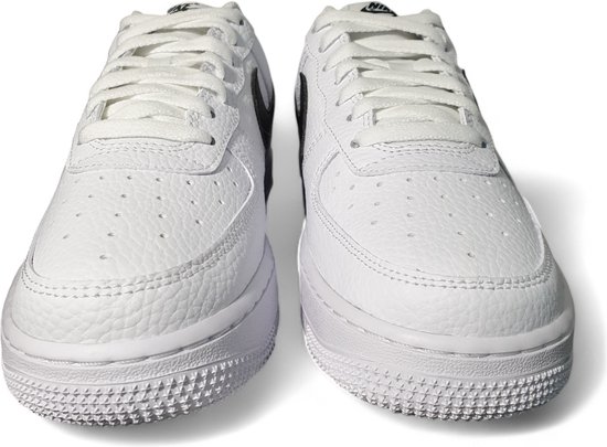 Vooraanzicht van een paar witte sneakers van generfd leer met zwart Swoosh logo.