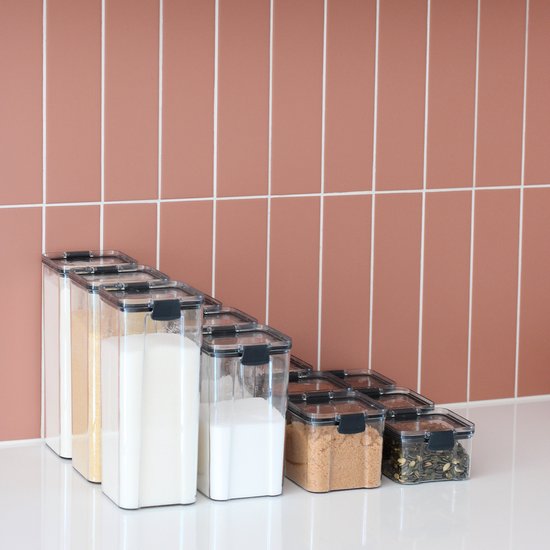 Rij van transparante voorraadpotten, gevuld met ingrediënten, opgesteld in aflopende grootte.
