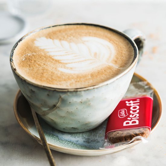 Lotus Biscoff speculaasje naast een kopje koffie met latte art.