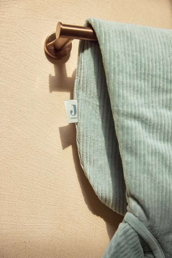 Label met het Jollein logo op een lichtgroene baby slaapzak met ribbelstructuur.