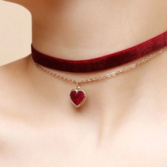 Een rode fluwelen choker met een gouden ketting en een rood hartvormig hangertje.