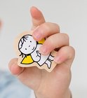 Houten engel met gele achtergrond, vastgehouden door een kinderhand.