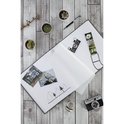 Open grijs album op een houten achtergrond met plantjes, een pen en een camera.