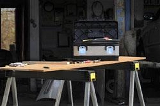 Werkbank met twee zwarte zaagbokken, houten planken en een gereedschapskist.