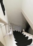 Witte trapleuning boven zwarte trapkussens, uitzicht naar beneden.