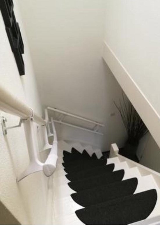 Witte trapleuning boven zwarte trapkussens, uitzicht naar beneden.