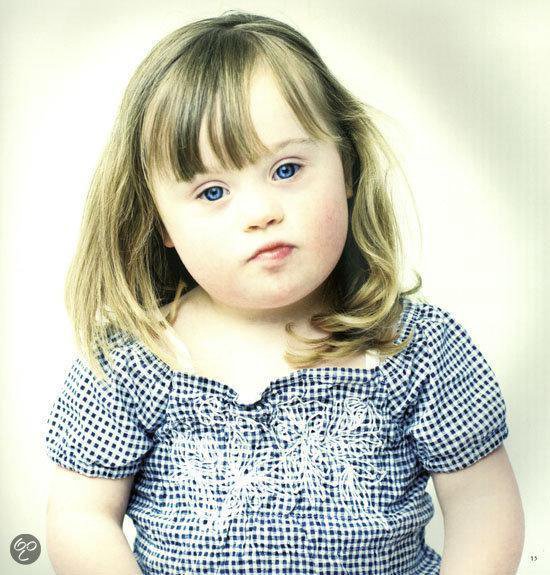 Een jong meisje met blond haar en blauwe ogen, draagt een blauw-wit geruit shirt met witte borduursels.