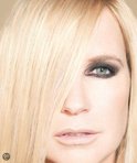 Vrouw met lang blond haar, waarvan een deel over haar gezicht valt. Zwart-wit.