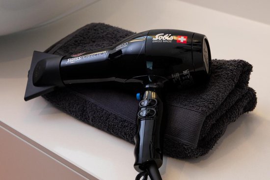 Zwarte Solis föhn met stylingopzetstuk, liggend op een donkergrijze handdoek.
