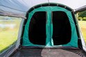 Binnenkant van een groene familietent met zicht op twee zwarte slaapcabines met ritssluiting.
