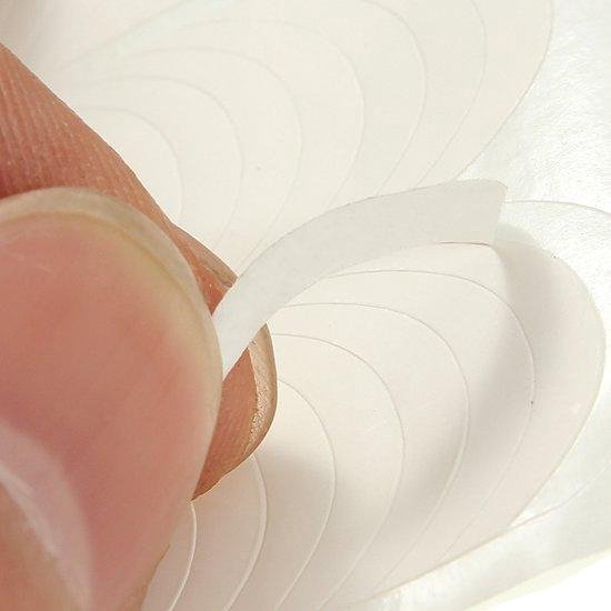 Vinger toont een witte Franse manicure sticker, een deel is losgetrokken.