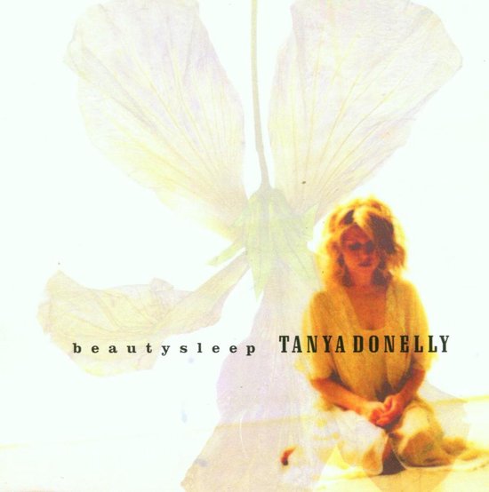 Tanya Donelly zit op de grond in een gele jurk, met een grote, doorschijnende bloem op de achtergrond. De tekst 'beautysleep TANYA DONELLY' staat erbij.