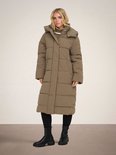Model draagt bruine lange pufferjas met capuchon.