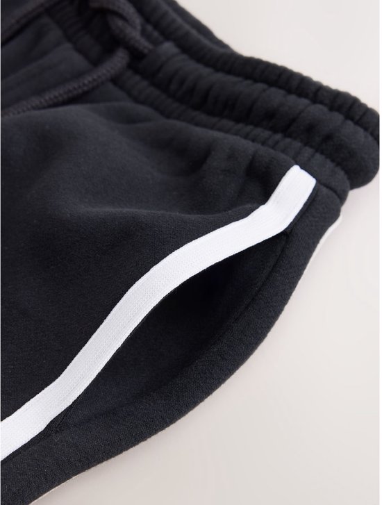 Zwarte joggingbroek met witte bies langs de steekzak.