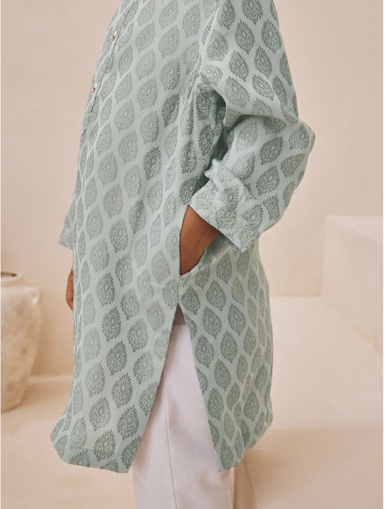Zijaanzicht van een lichtgroene kurta met bladpatroon, voorzien van zijzakken en witte broek.