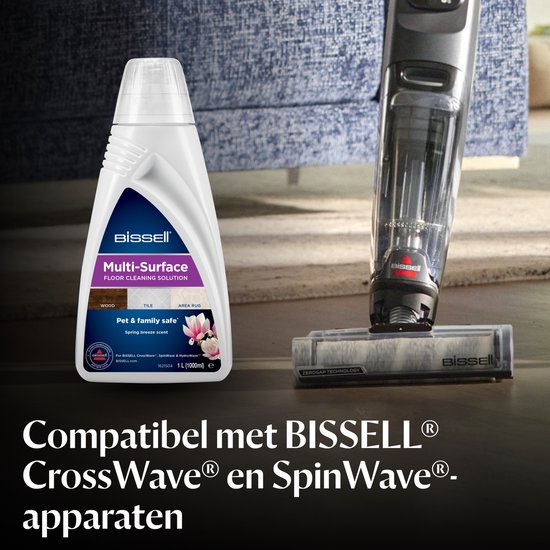 BISSELL reinigingsmiddel en stofzuiger naast een blauwe bank.